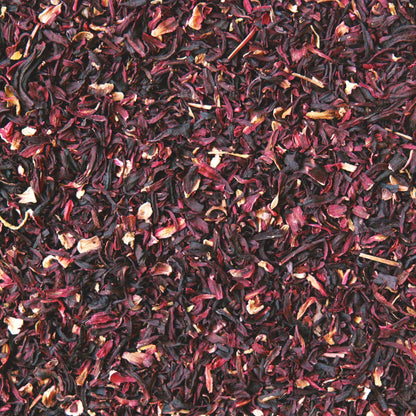 A close up view of herbal loose leaf tea. The image is specifically of dried cut hibiscus flower. It's showing it dark and bright red tones. 
